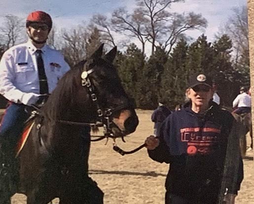 A veteran on a horse being lead by a volunteer